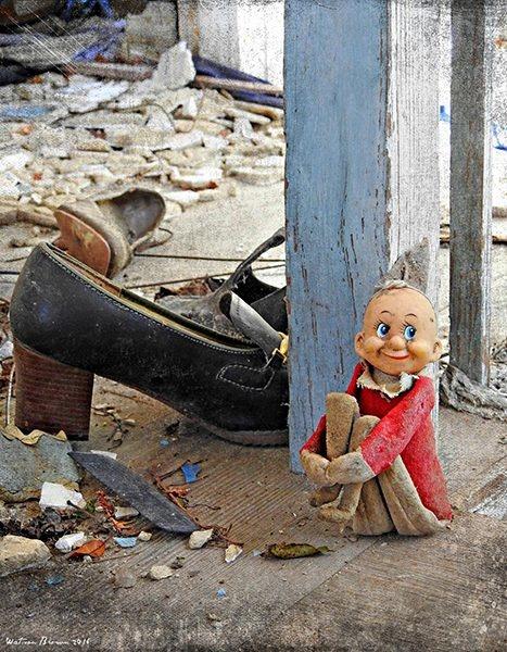 A doll wearing red clothings surrounded by other abandoned items including a shoe
