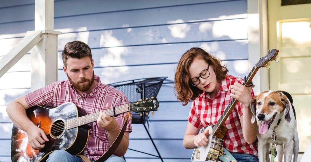 Sarah and Austin McCombie sit on their front porch, playing a guitar and a banjo. Hound dog Ruby joins them.