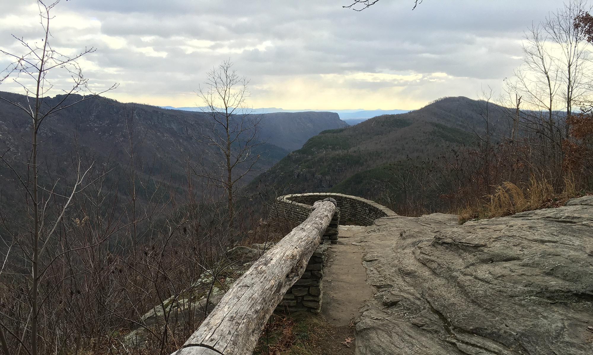 A photo of a tree log divider running along the edge of a mountain range. More mountains can be seen in the distance.