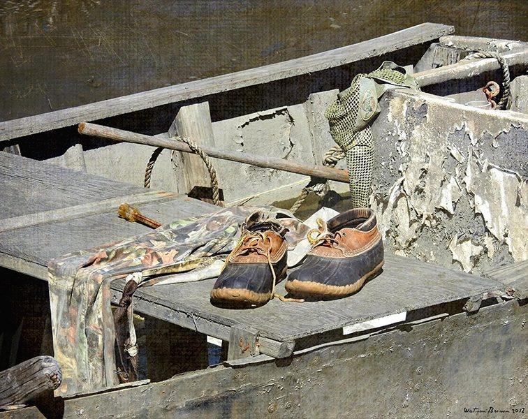 A pair of shoes sits on top of an broken down boat