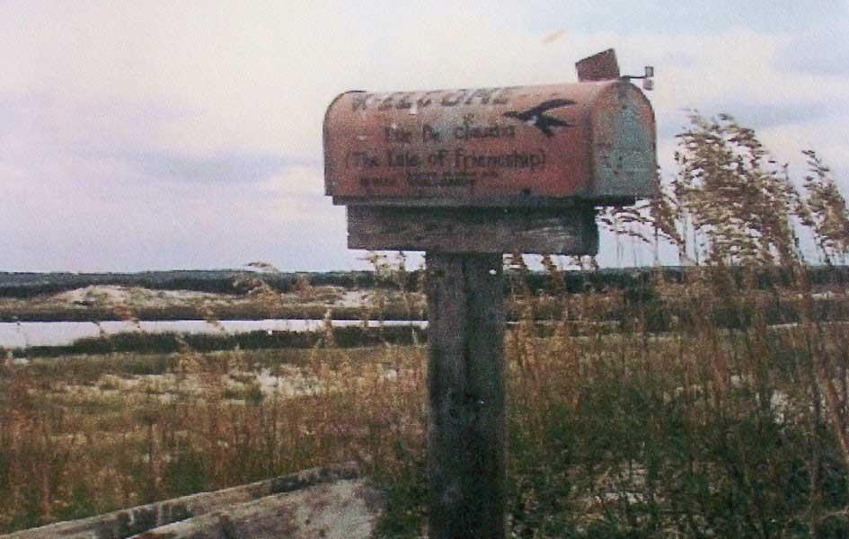 old photograph of a mailbox on a wood post with seagrass surrounding it and in the background
