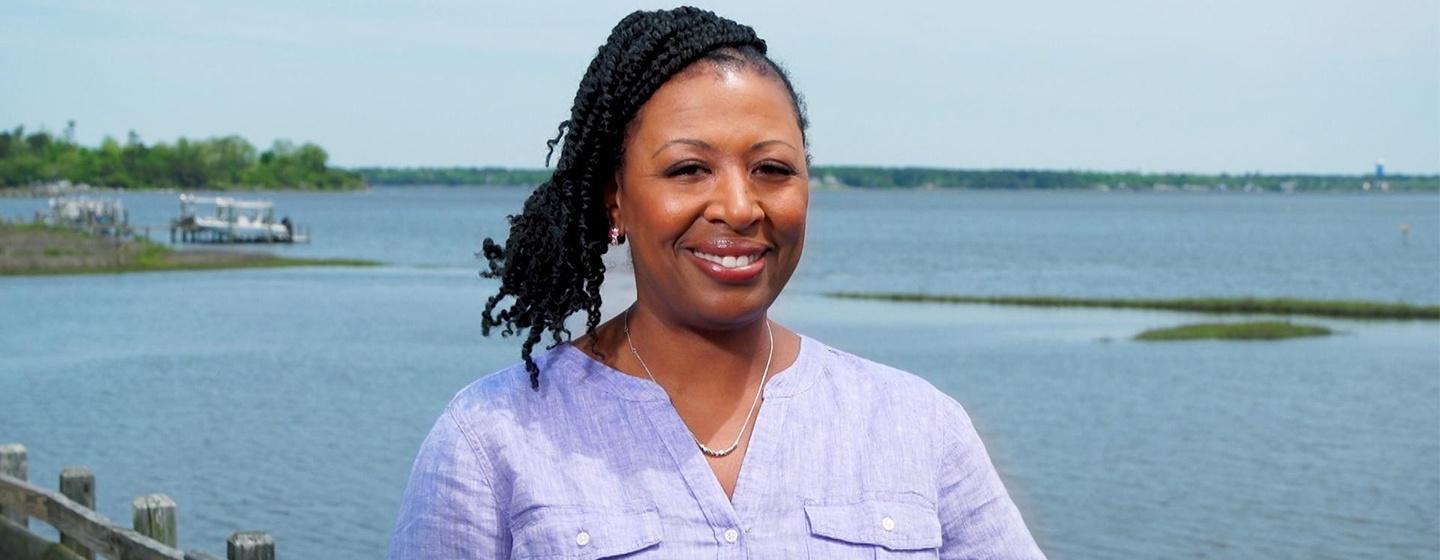 Deborah Holt Noel smiling towards the camera in a light purple button up shirt.