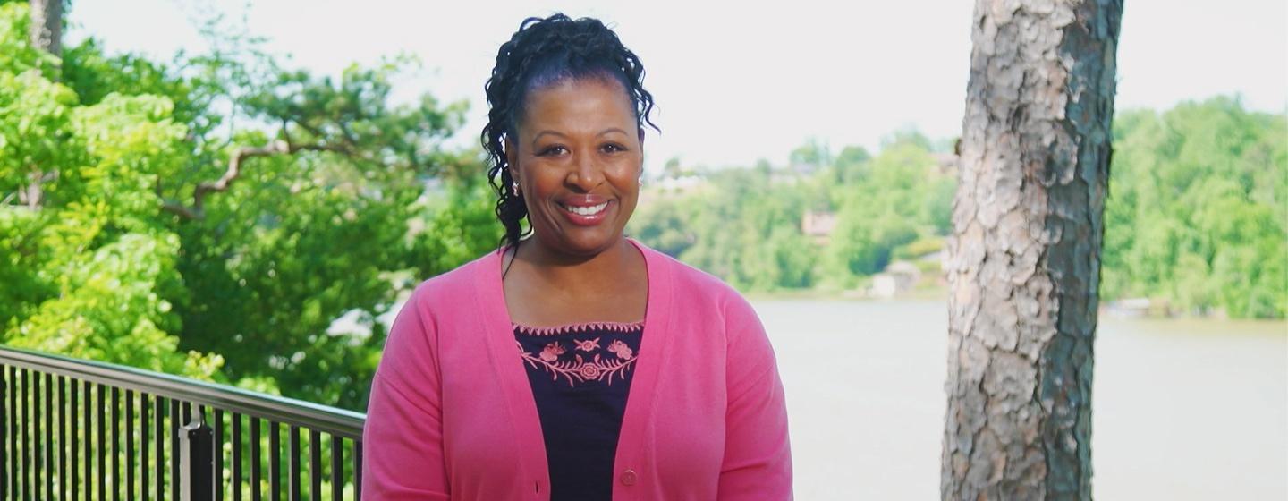 Deborah Holt Noel smiling at the camera in a soft pink cardigan and black top.