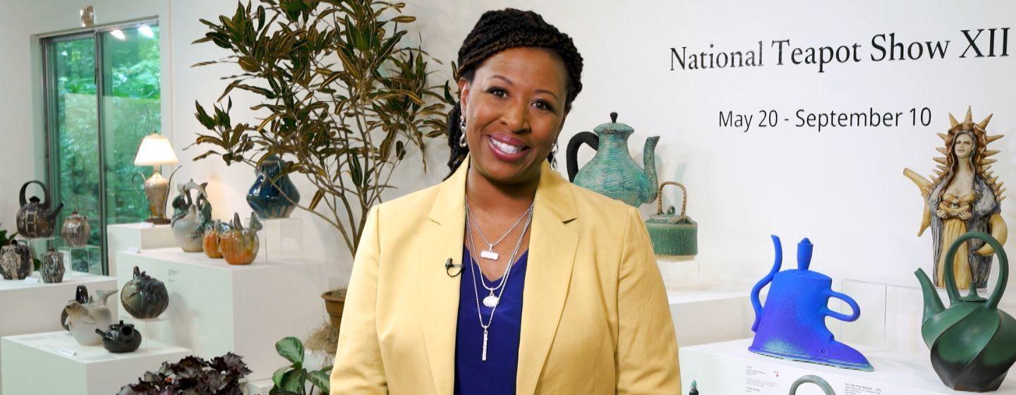 Deborah Holt Noel smiles in front of the camera wearing a royal blue shirt and yellow blazer