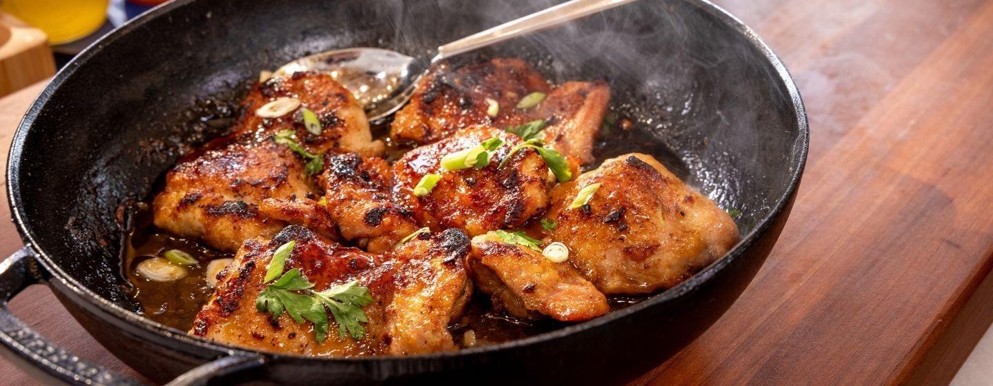 Honey-glazed chicken thighs in a cast iron pan.