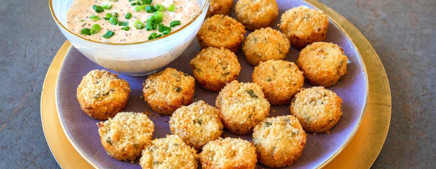 A close up of a platter of crab cake bites and a bowl of rémoulade sauce.