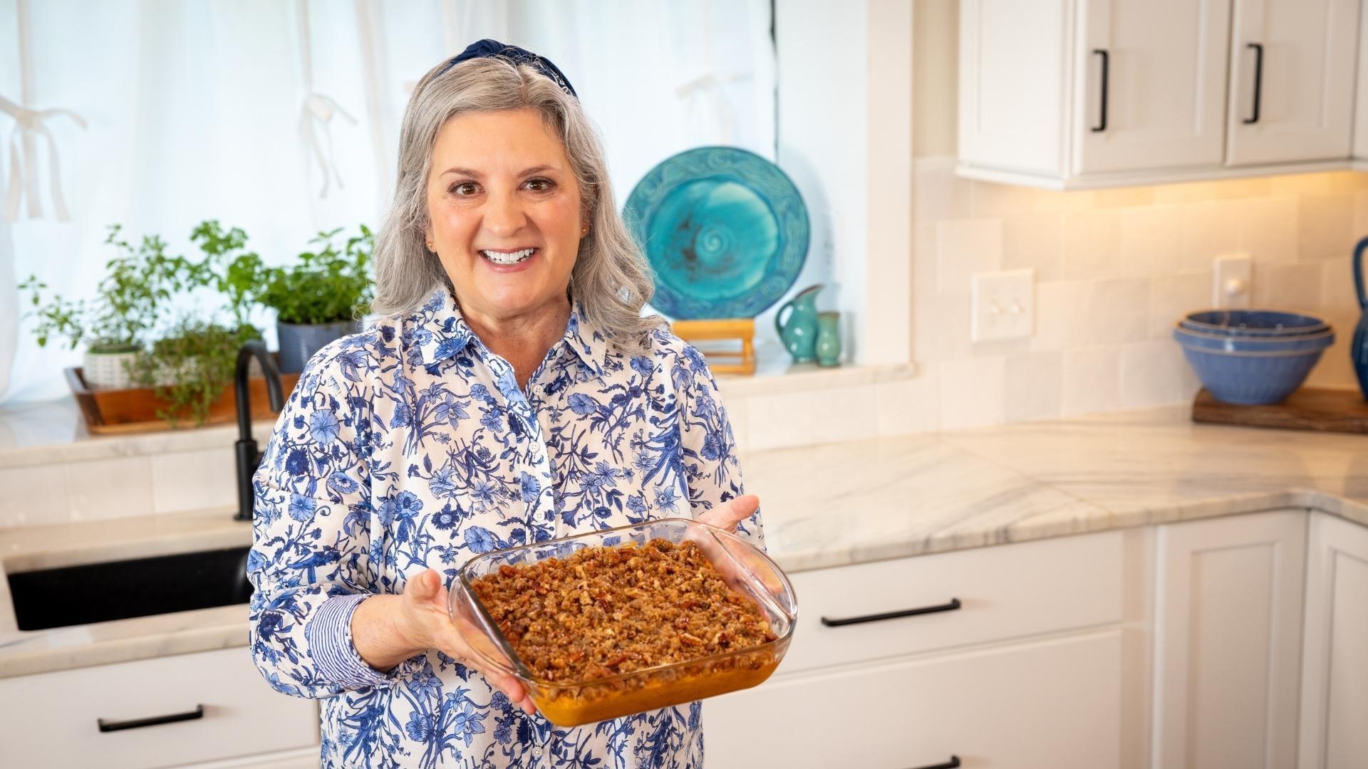 Sheri Castle holding up a glass baking dish of sweet potato casserole.