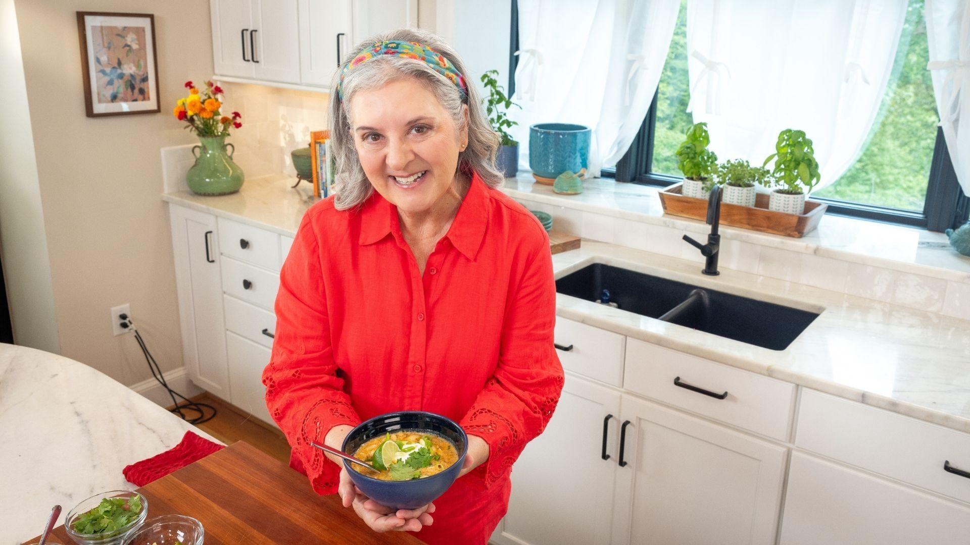 Sheri Castle holding up a bowl of white bean and chile stew.