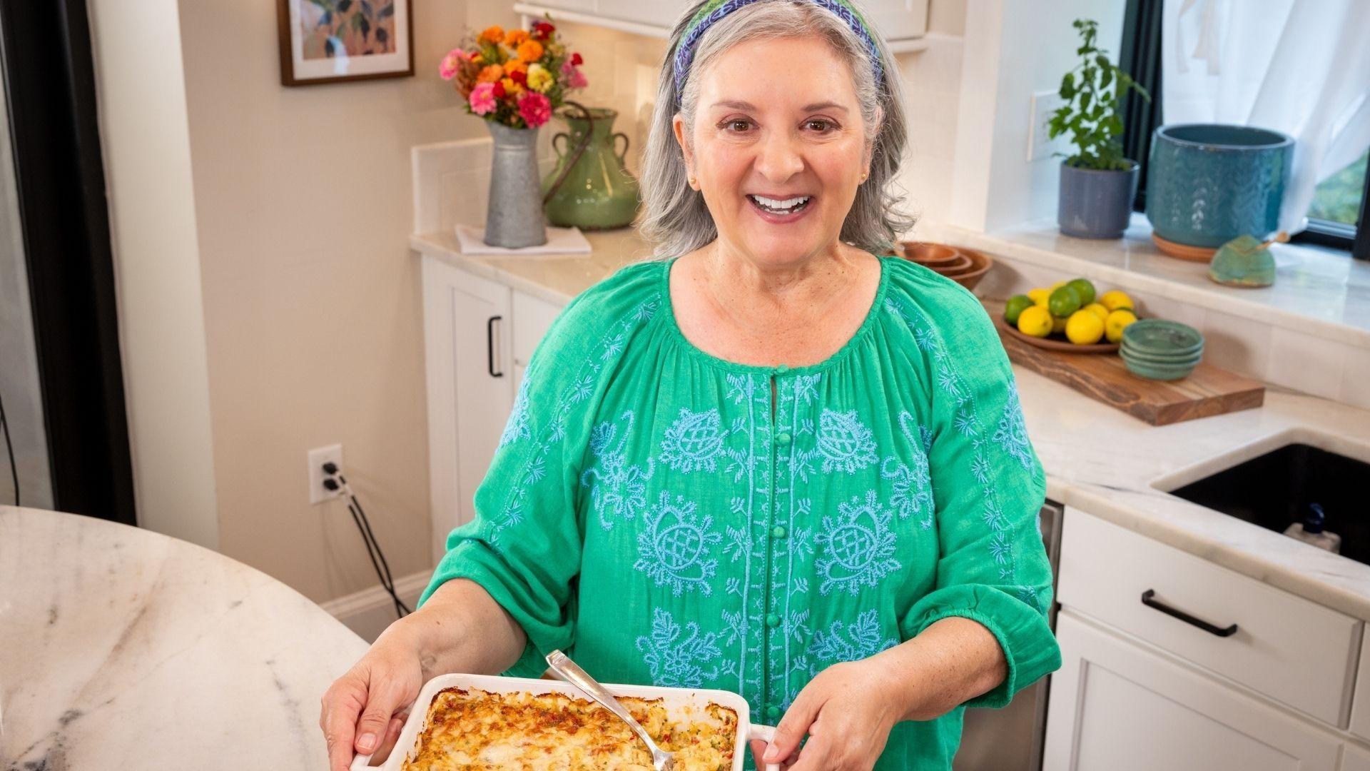 Sheri Castle holding up a baking dish of warm crab dip.