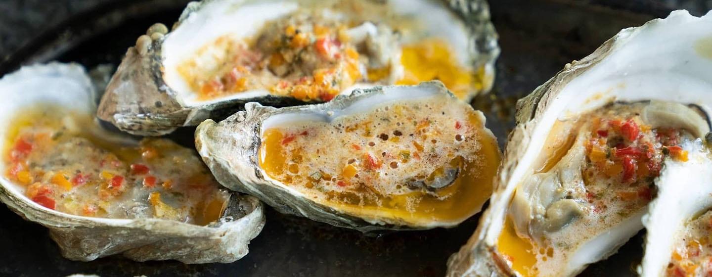 Closeup of roasted oysters with butter on top