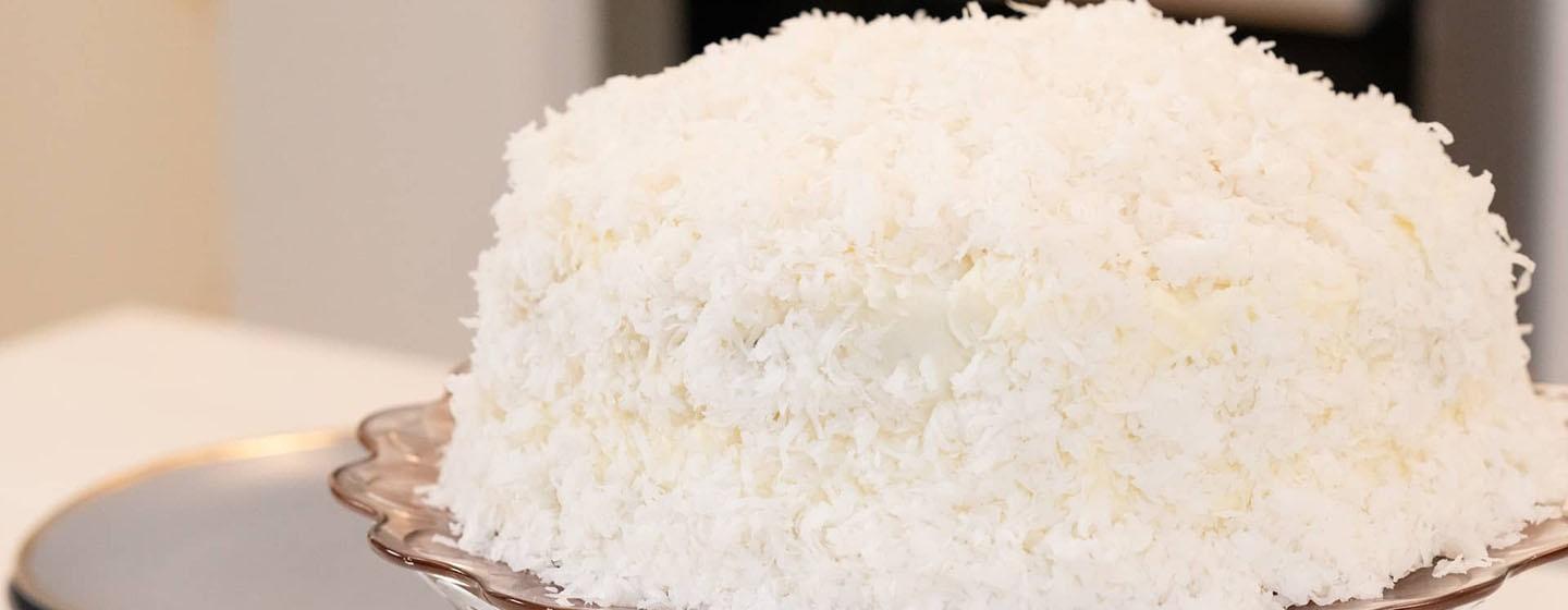 Coconut Layer Cake sitting on top of gray platter