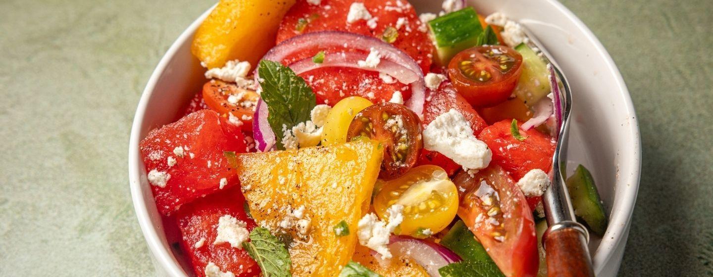 Watermelon Salad with Margarita Dressing in a white ceramic bowl on a light green surface.