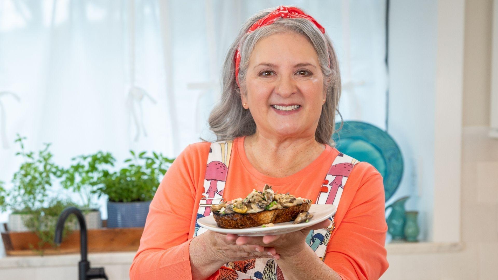 Sheri Castle holding up a plate of mushrooms on toast.