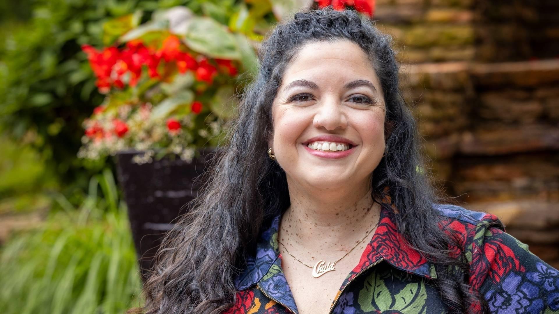 Von Diaz smiling in front of a garden.