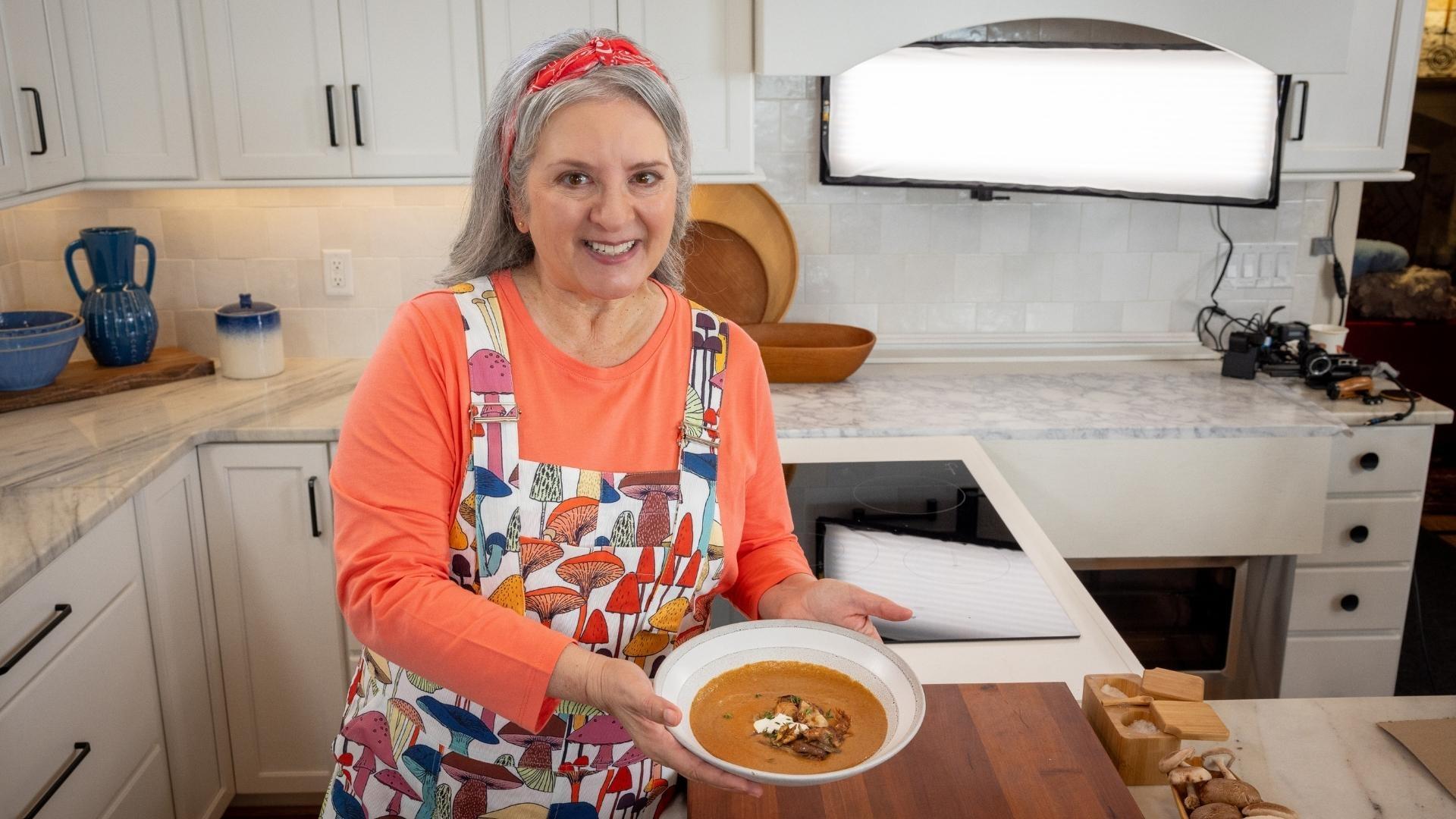 Sheri Castle holding up a bowl of double mushroom soup.