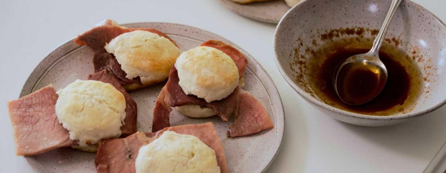 A plate of biscuits and ham and a bowl of red-eye gravy