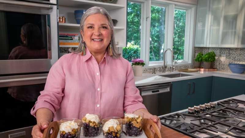 Sheri Castle smiles brightly and holds a platter of blueberry parfaits