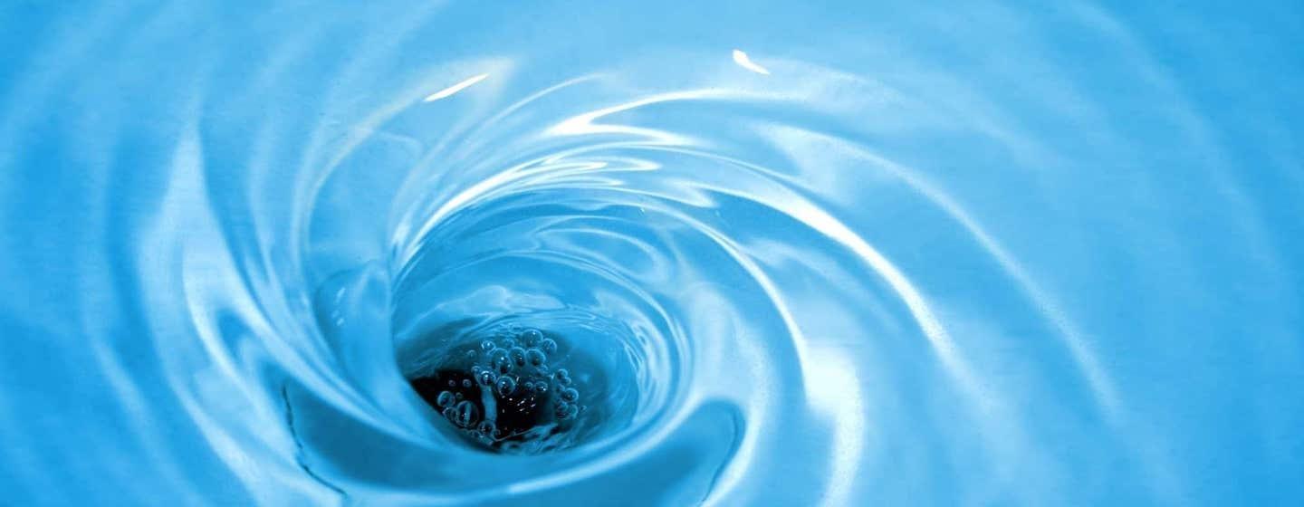 water spinning down drain in blue whirlpool