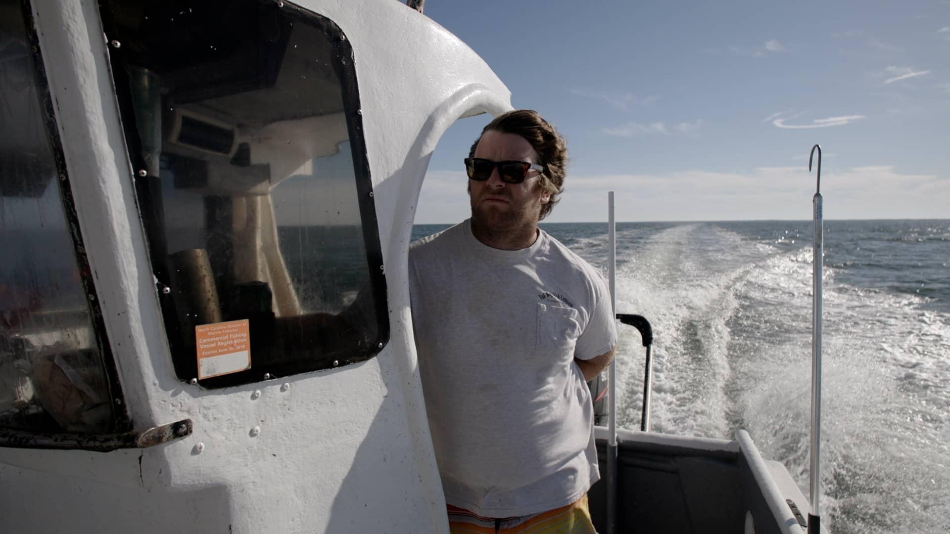 morty gaskill man stands on motor boat deck with sunglasses