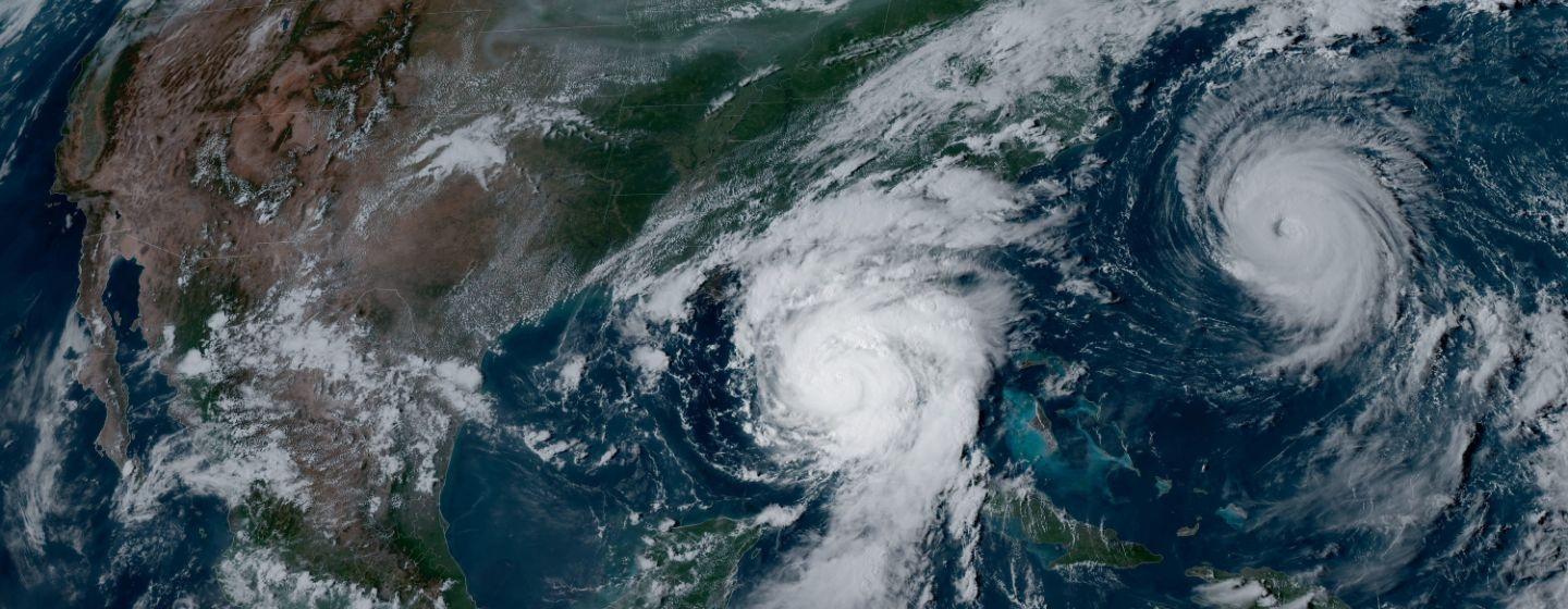 A satellite image showing North America and the North Atlantic Ocean with two large hurricanes.