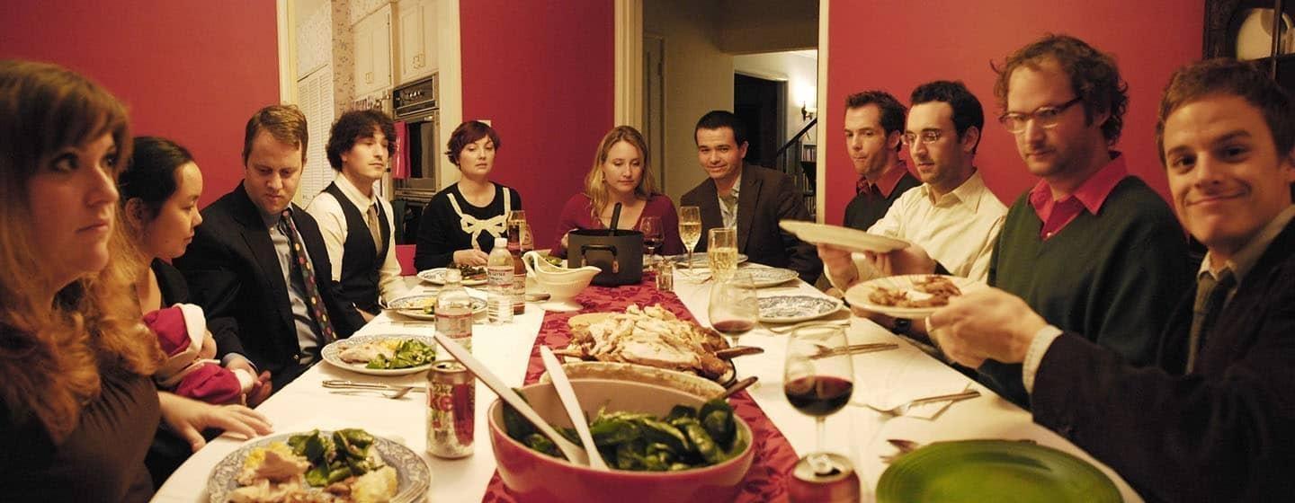 family gatherin sitting in red dining room for holiday dinner