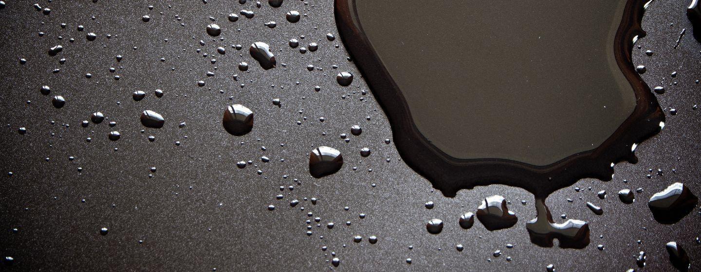 A dark wet puddle and droplets on a black background.