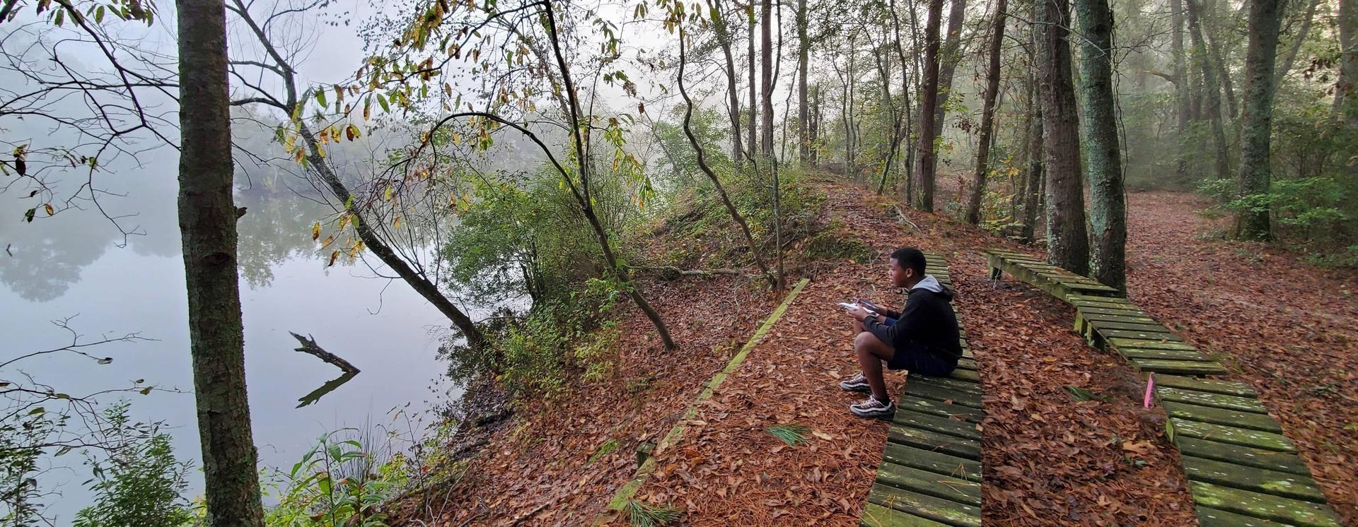 kid reading book on wooden bench at misty lake edge