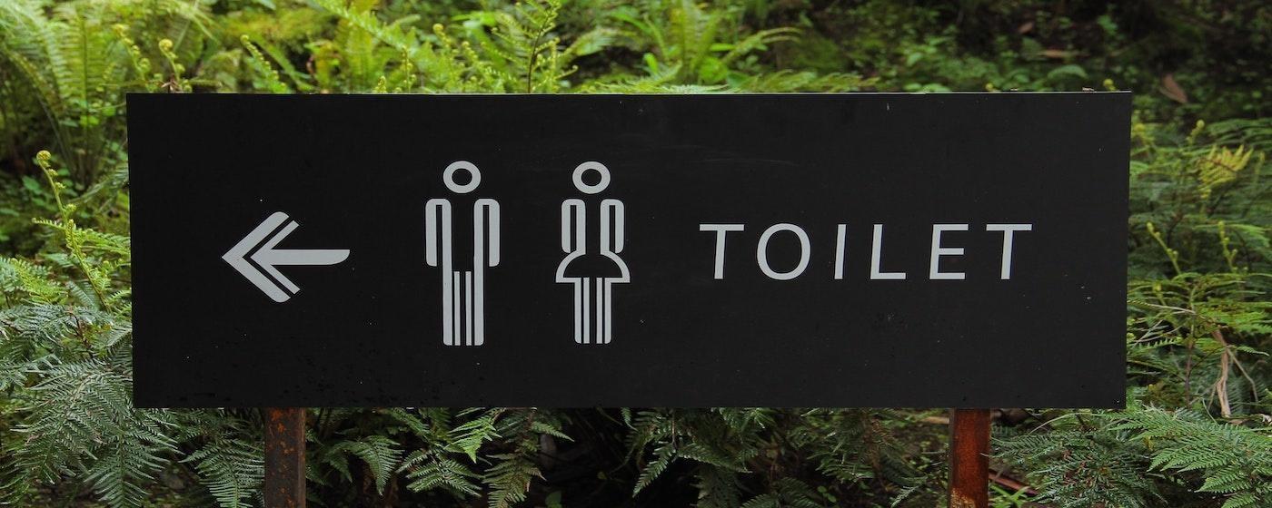 outdoor restroom toilet sign men and women with ferns in background