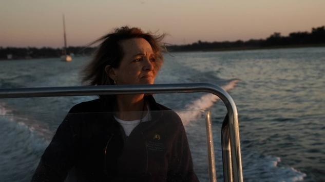 woman on motor boat at evening facing sunset