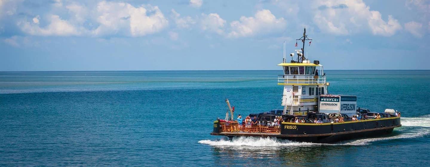 A ferry travels through water with a blue sky background