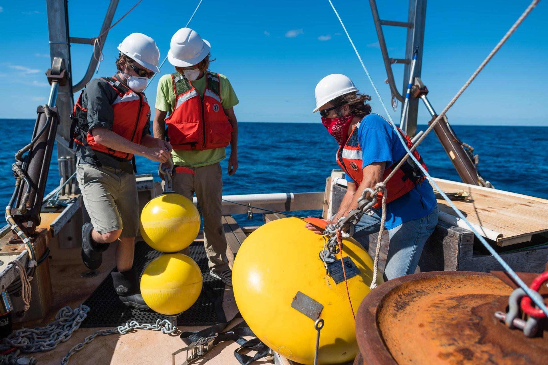 Research team prepping the buoy's anchor on the deck of a boat.
