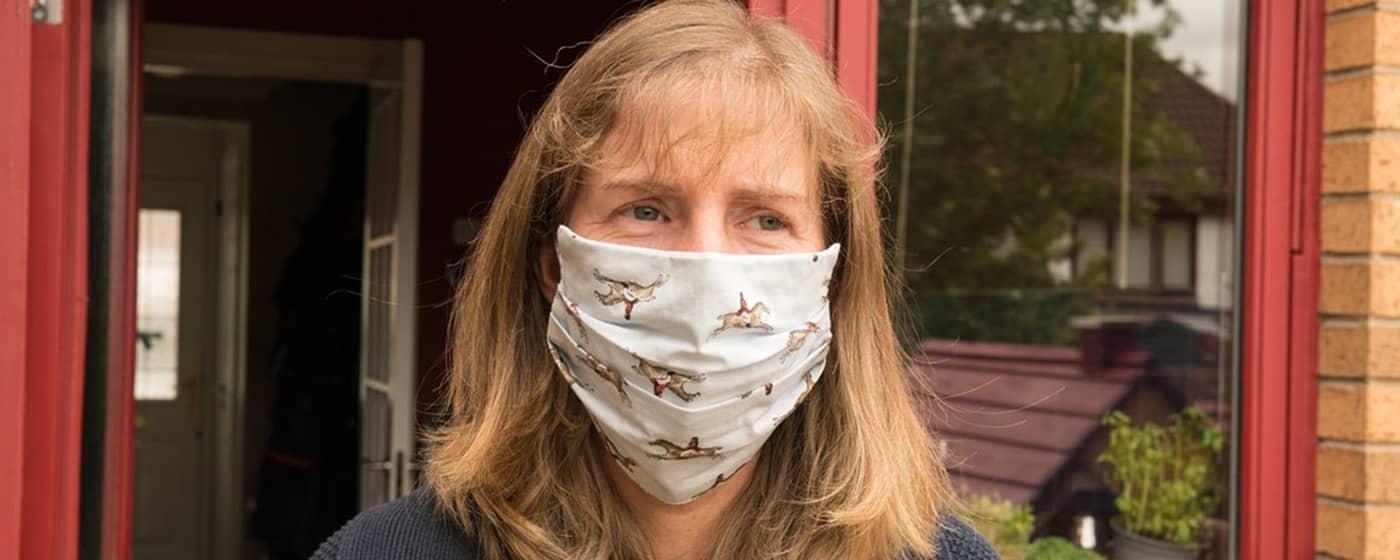woman wearing cloth mask in front of store window doorway