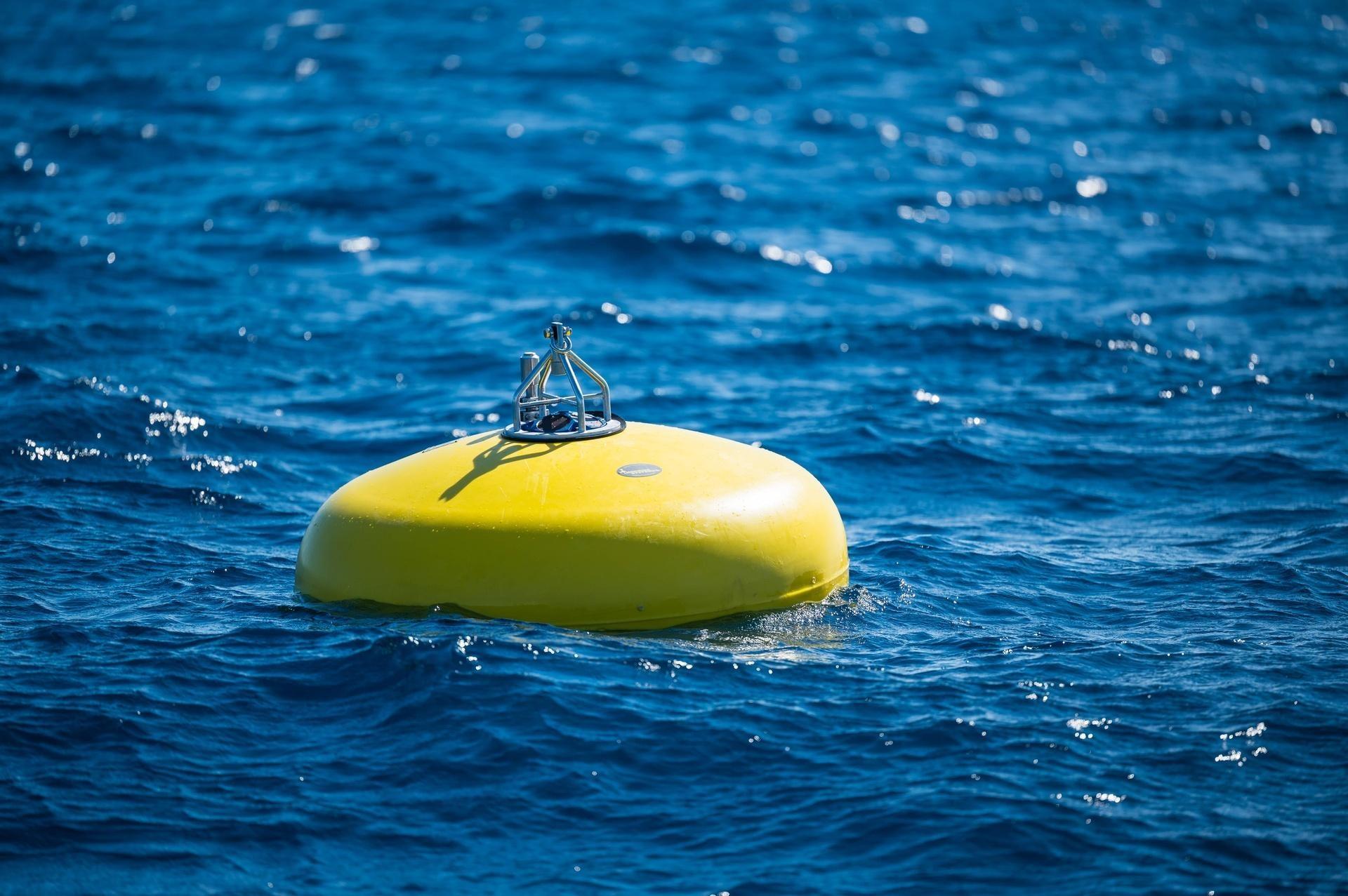 New buoy deployed on the ocean's surface. (yellow buoy on blue ocean)
