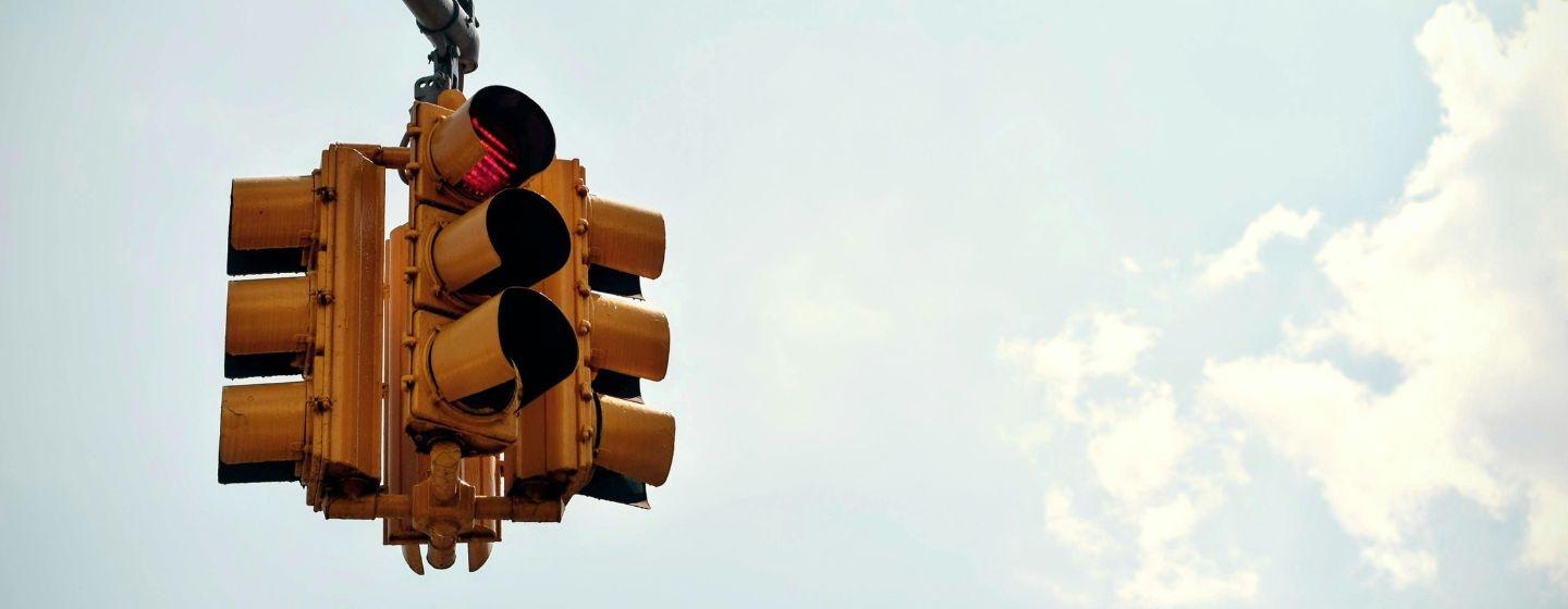 A four-way traffic light with the blue sky behind it.