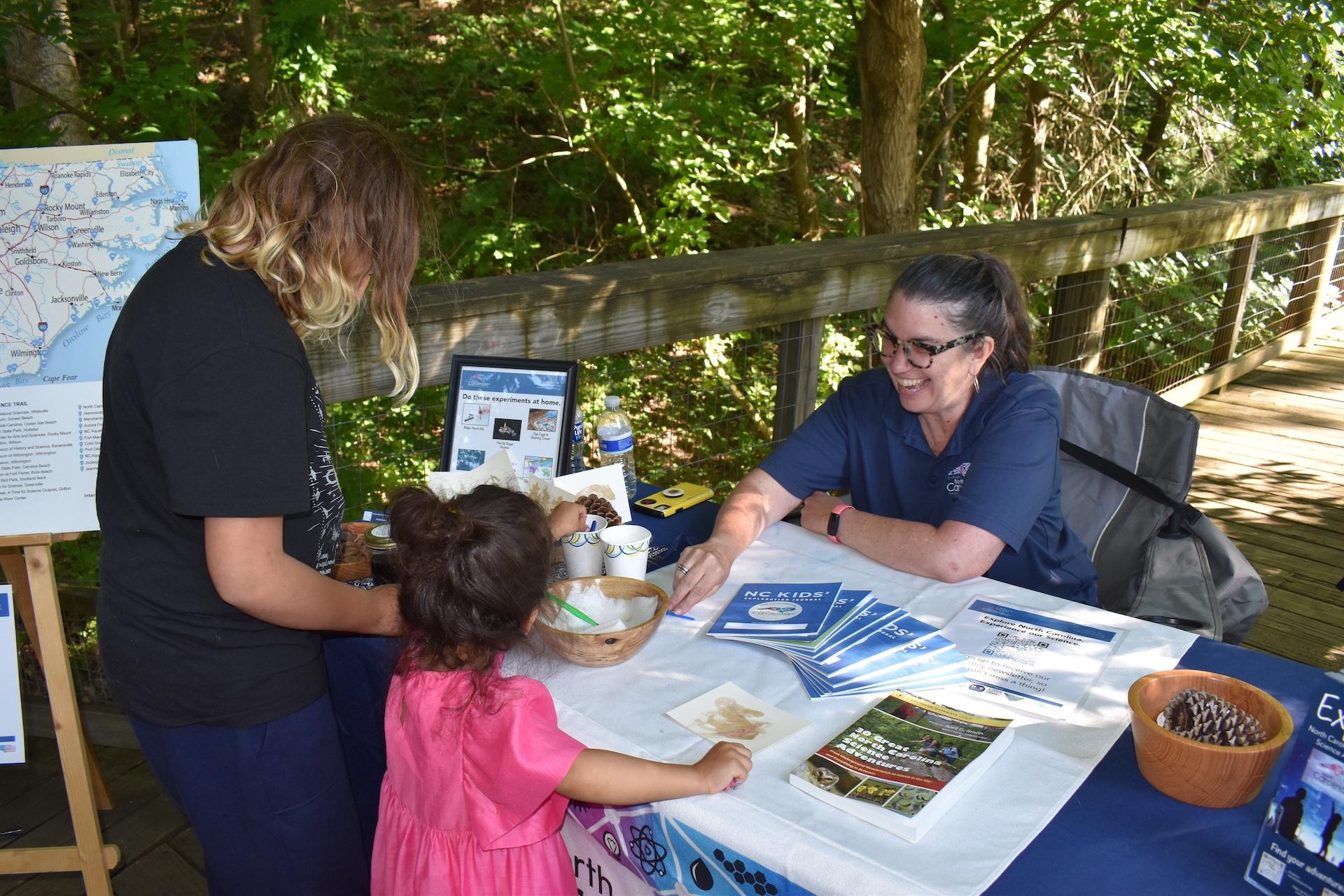 A child and adult interact with the NC Science Trail booth at the WNC Nature Center