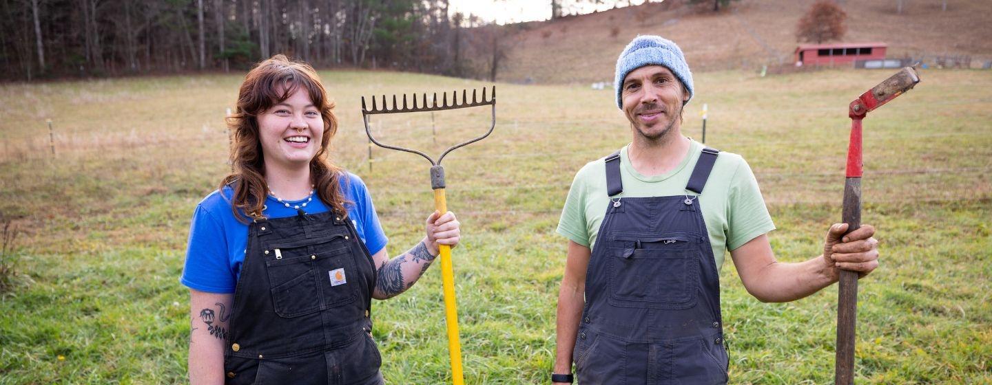 Leeza Chen with a farming hoe and Chris Smith with a digging toolstand in a field.
