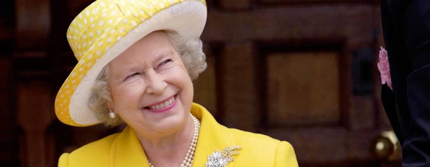 An image of Queen Elizabeth II wearing a yellow suit and yellow and white hat