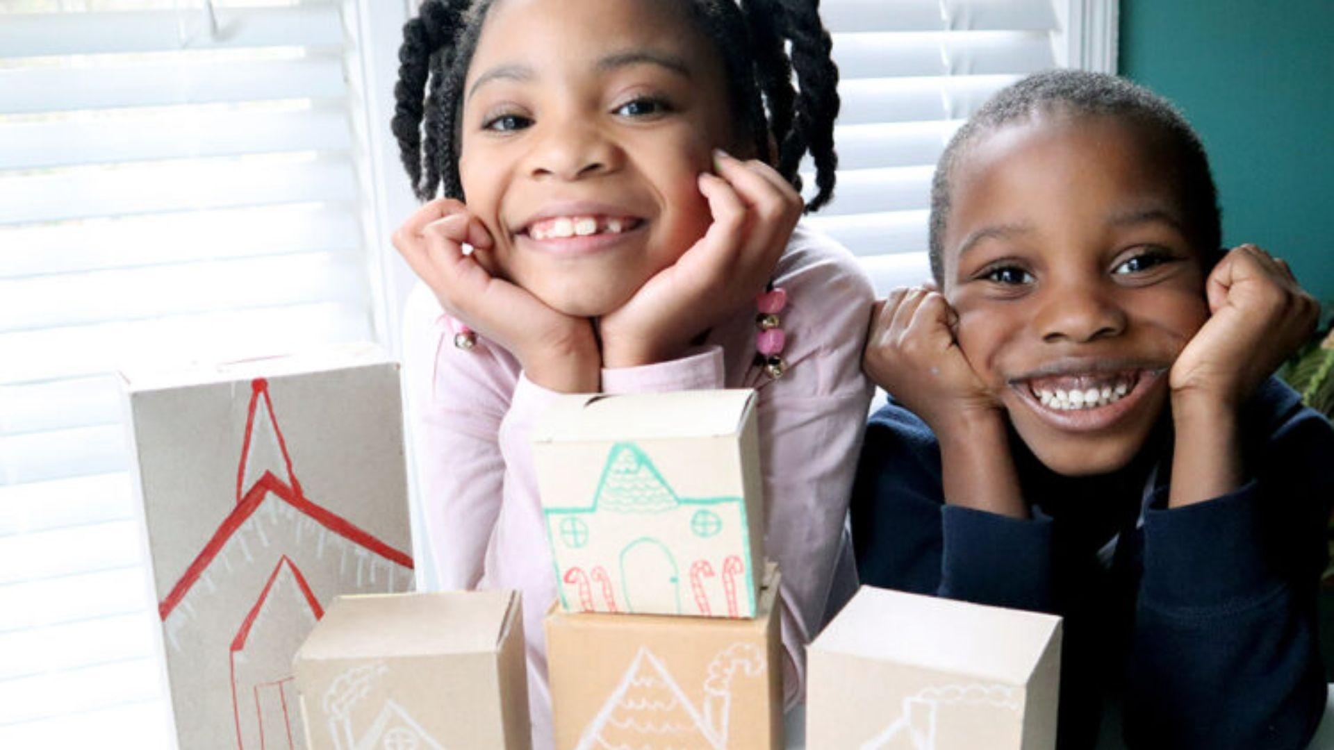 Two children showing off their homemade gingerbread village.