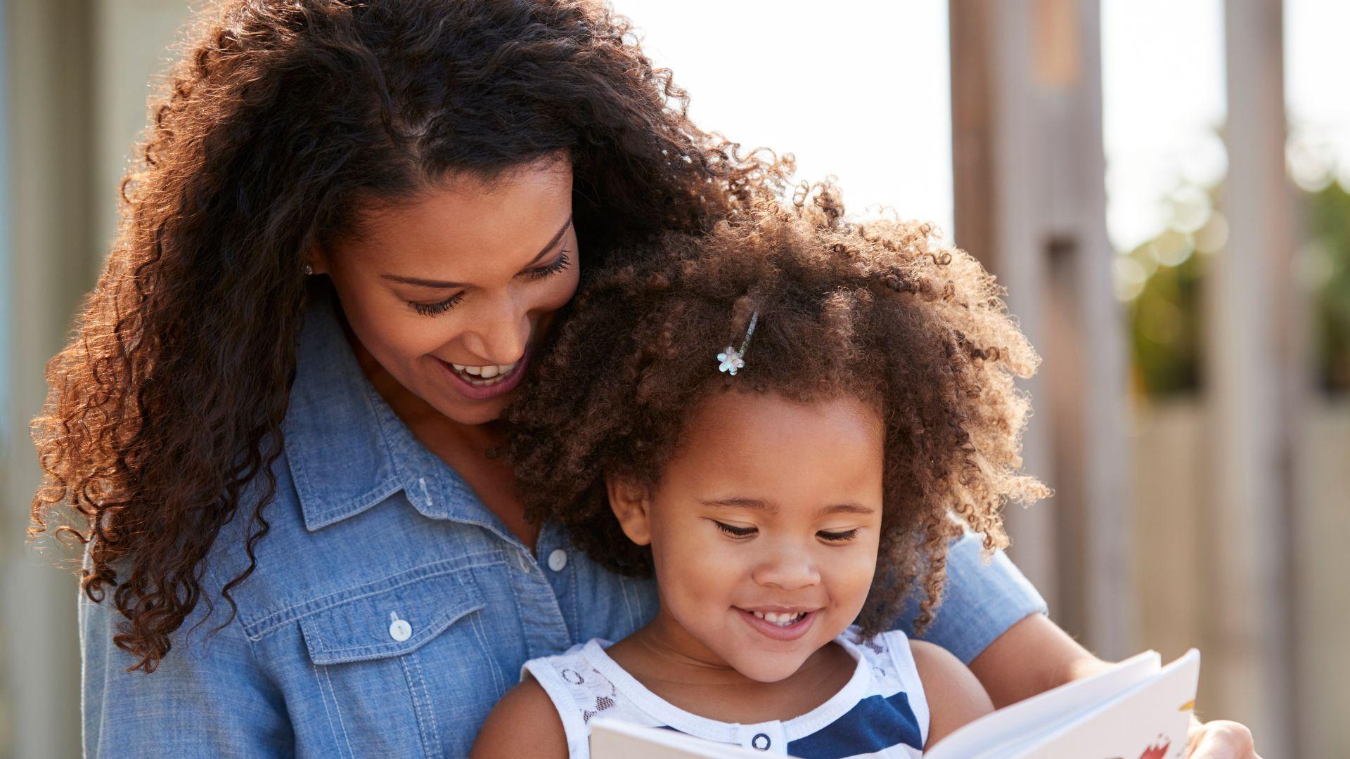 A black child sitting and reading with their mom.A black child sitting and reading with their mom.