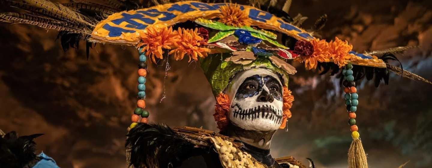 A closeup headshot of a person with traditional Día de los Muertos attire and makeup