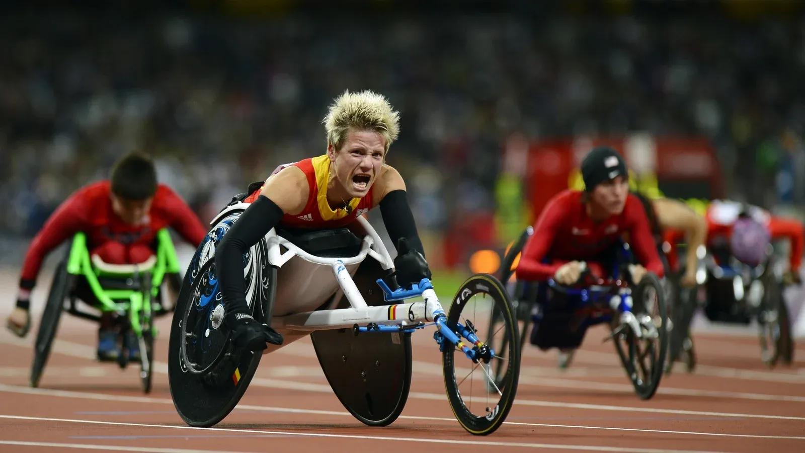 Wheelchair racing athletes competing on a track inside the Olympic Stadium.