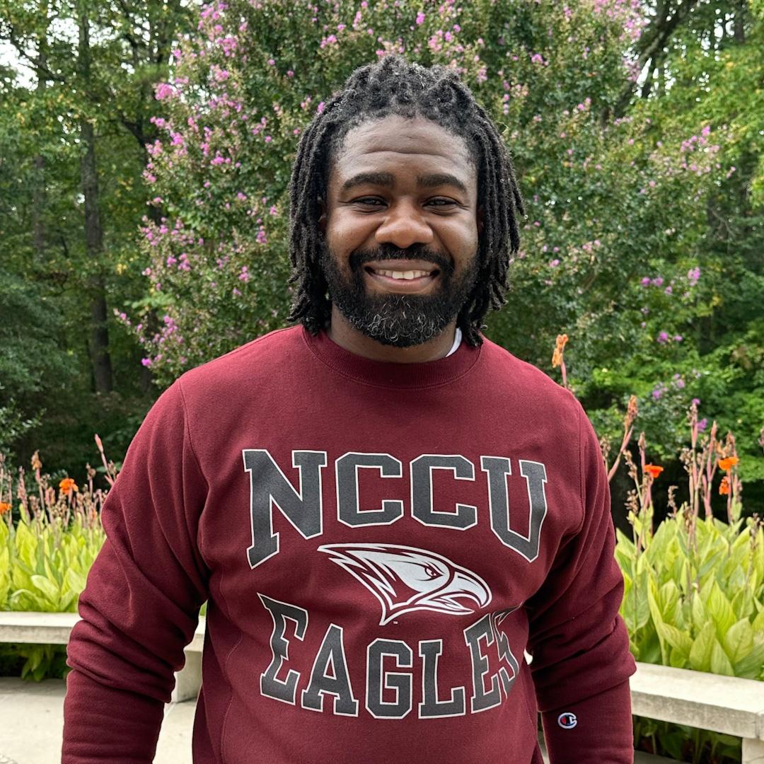 Reuben Affiah wearing a maroon crew neck sweatshirt that reads "NCCU EAGLES"  in grey and white.