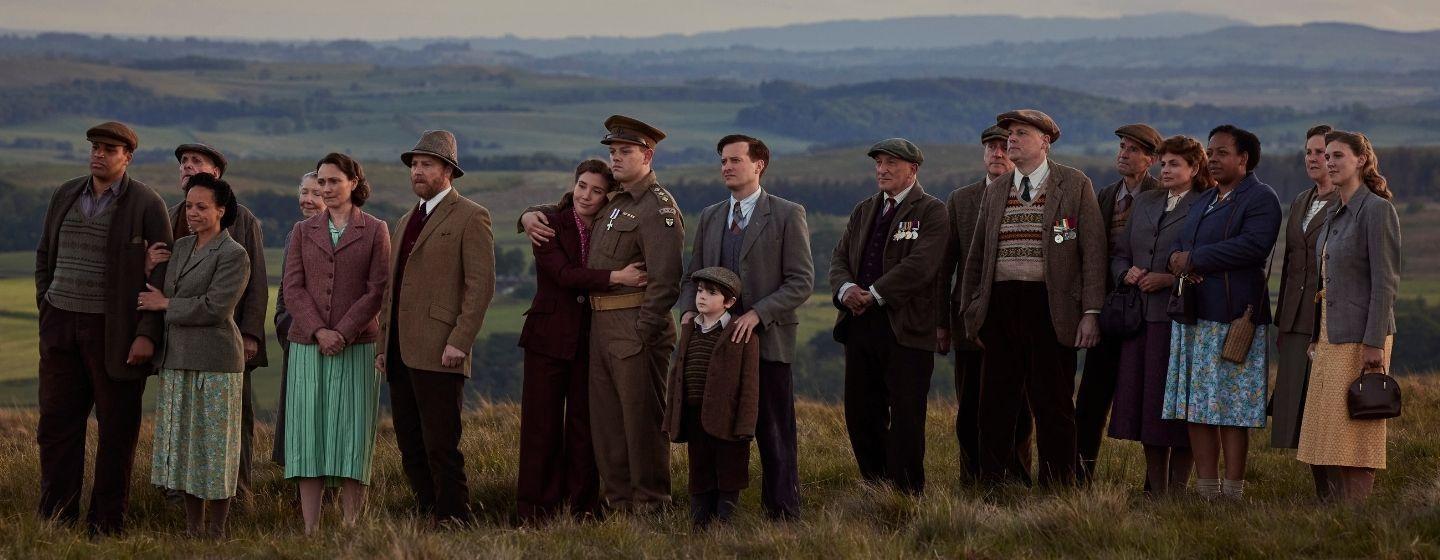 From L-R: Tom Chapman (Lamin Touray), Grace Chapman (Cat Simmons), Mrs. Hall (Anna Madeley), Siegfried Farnon (Samuel West), Charlotte Beauvoir (Gaia Wise), Tristan Farnon (Callum Woodhouse), Jimmy Herriot (Thomas Riches) and James Herriot (Nicholas Ralph).