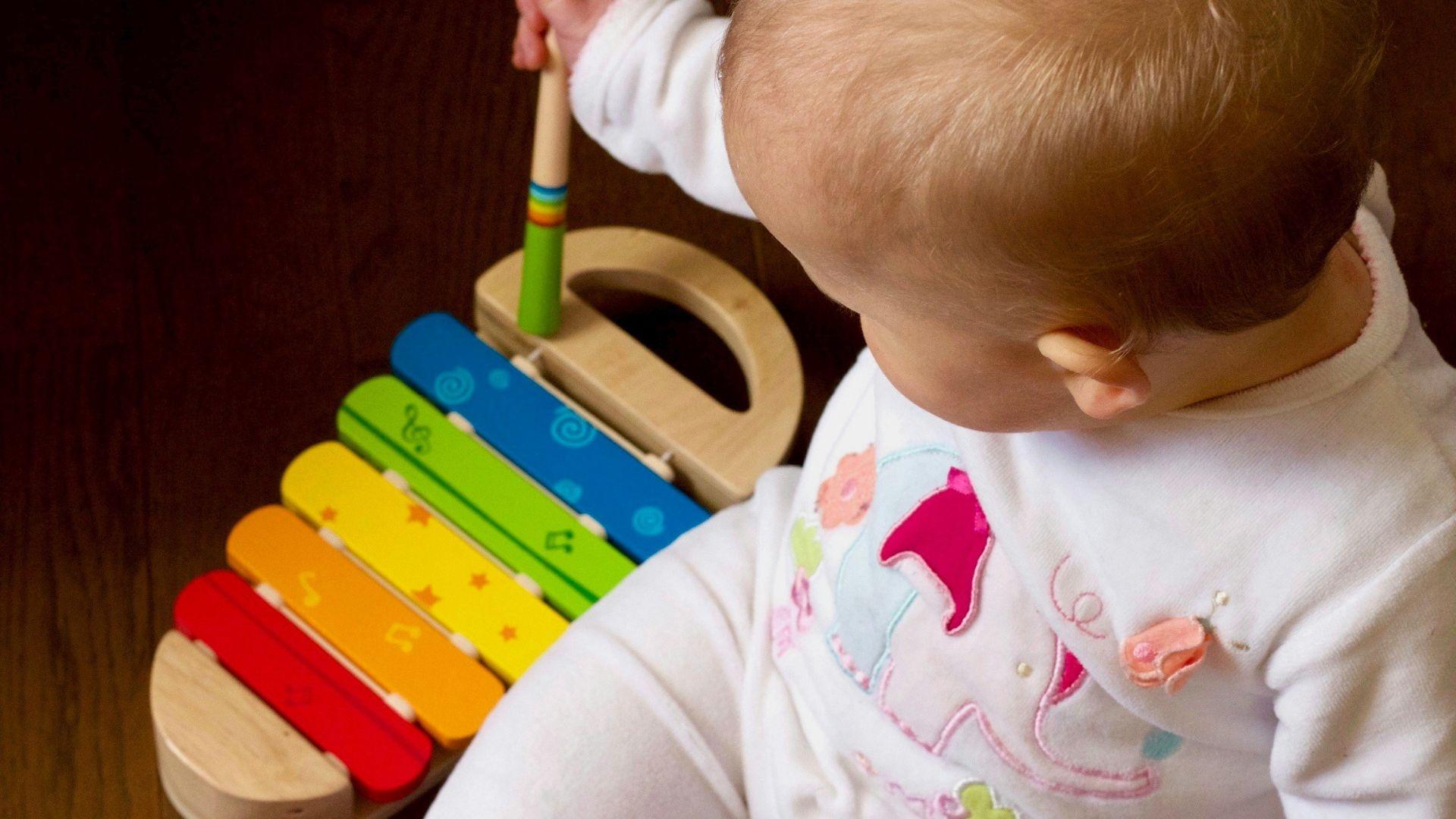 A baby plays on a rainbow xylophone.