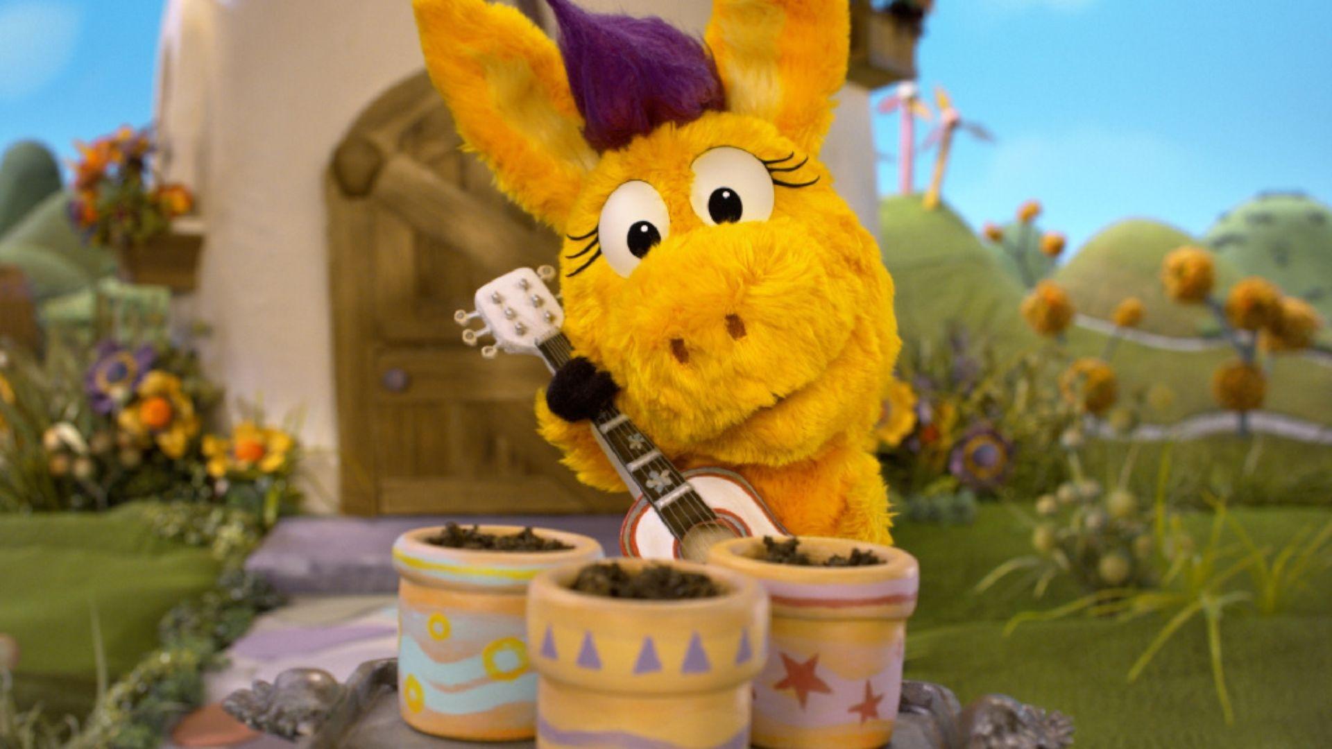 Donkey Hodie playing the guitar to some pots of soil.