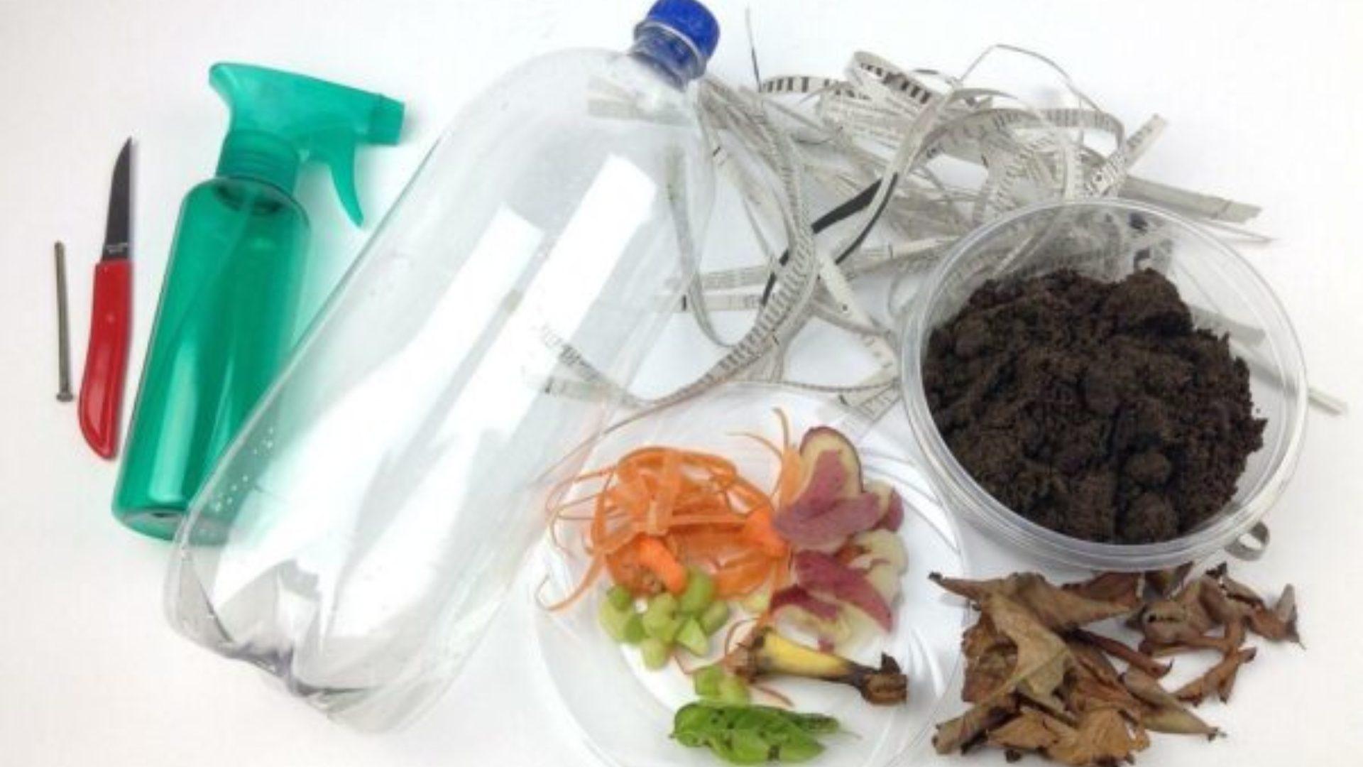 A nail, a small red knife, a plasstic spray bottle, a plastic soda bottle, some scraps of paper, food waste, soil and leaves laid out on a white surface.