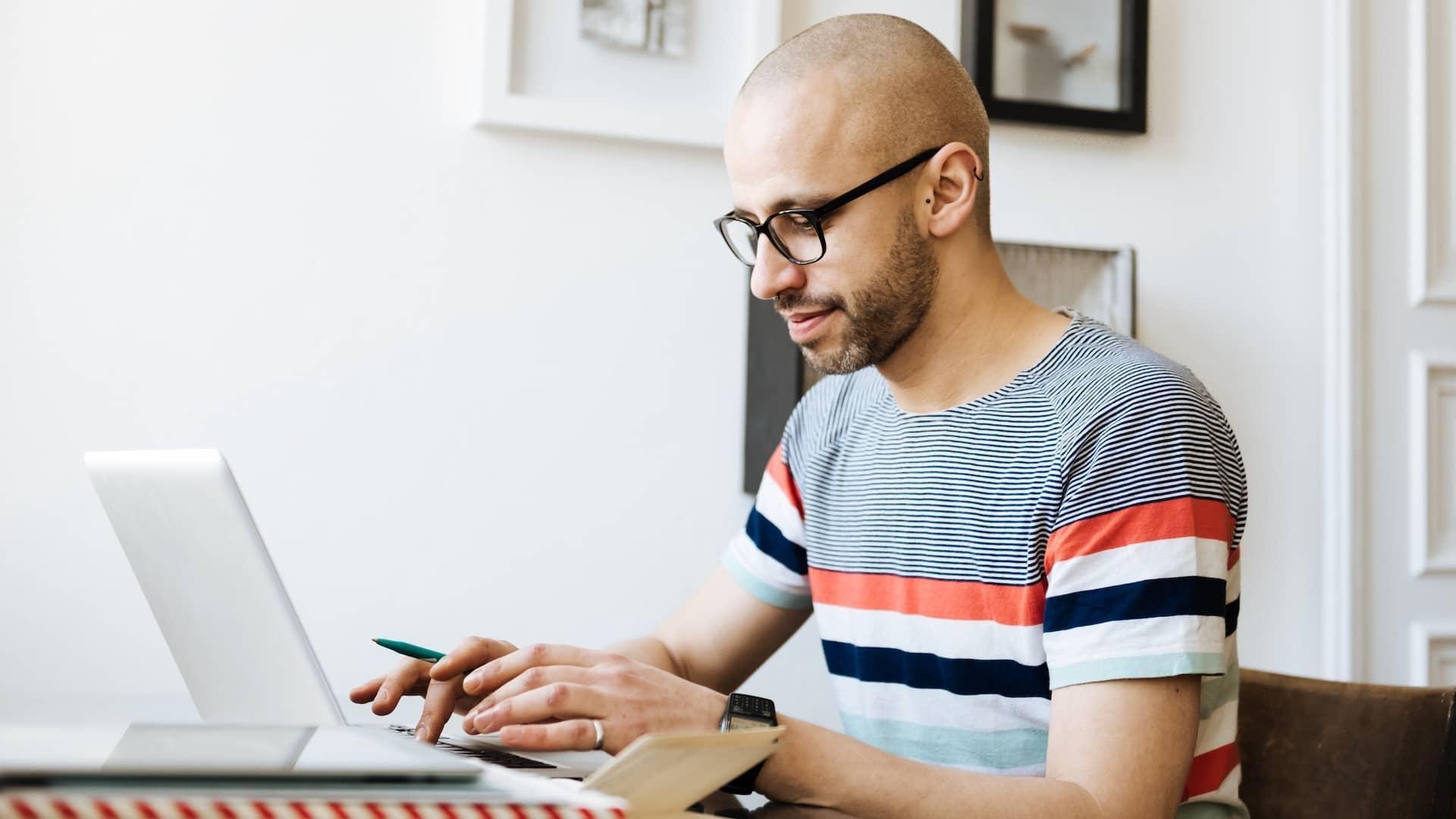 A man site at a desk in front of his laptop.