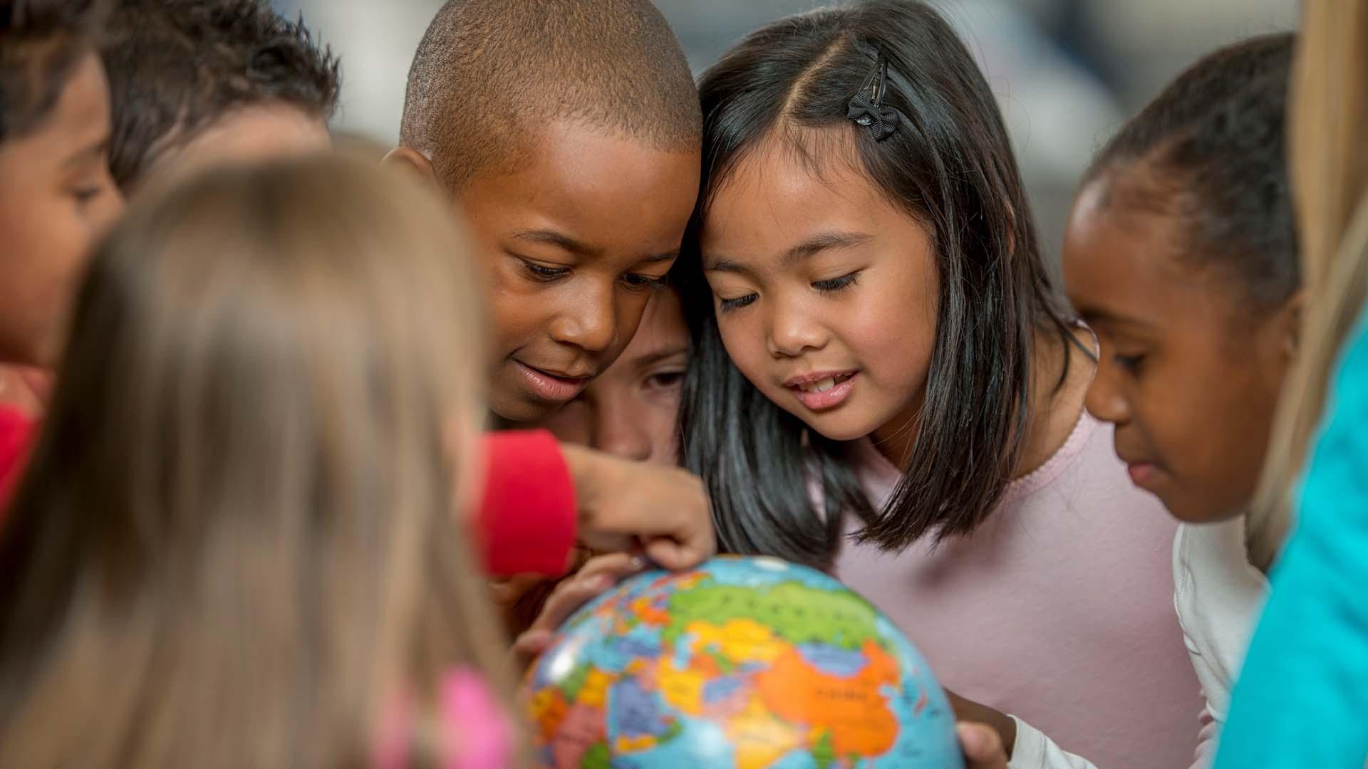 Small kids looking at a globe
