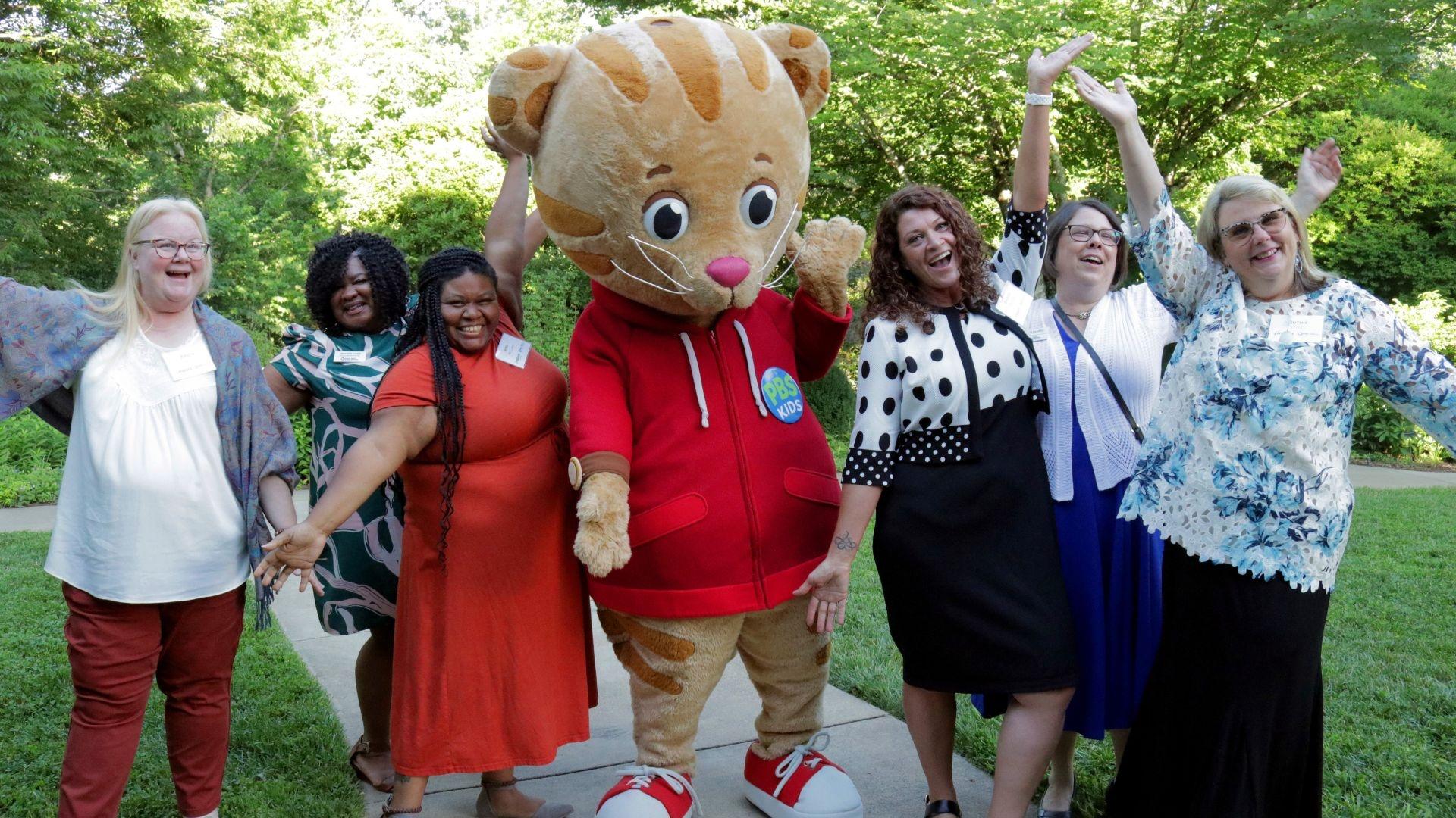 A ground of educators standing outside with Daniel Tiger.