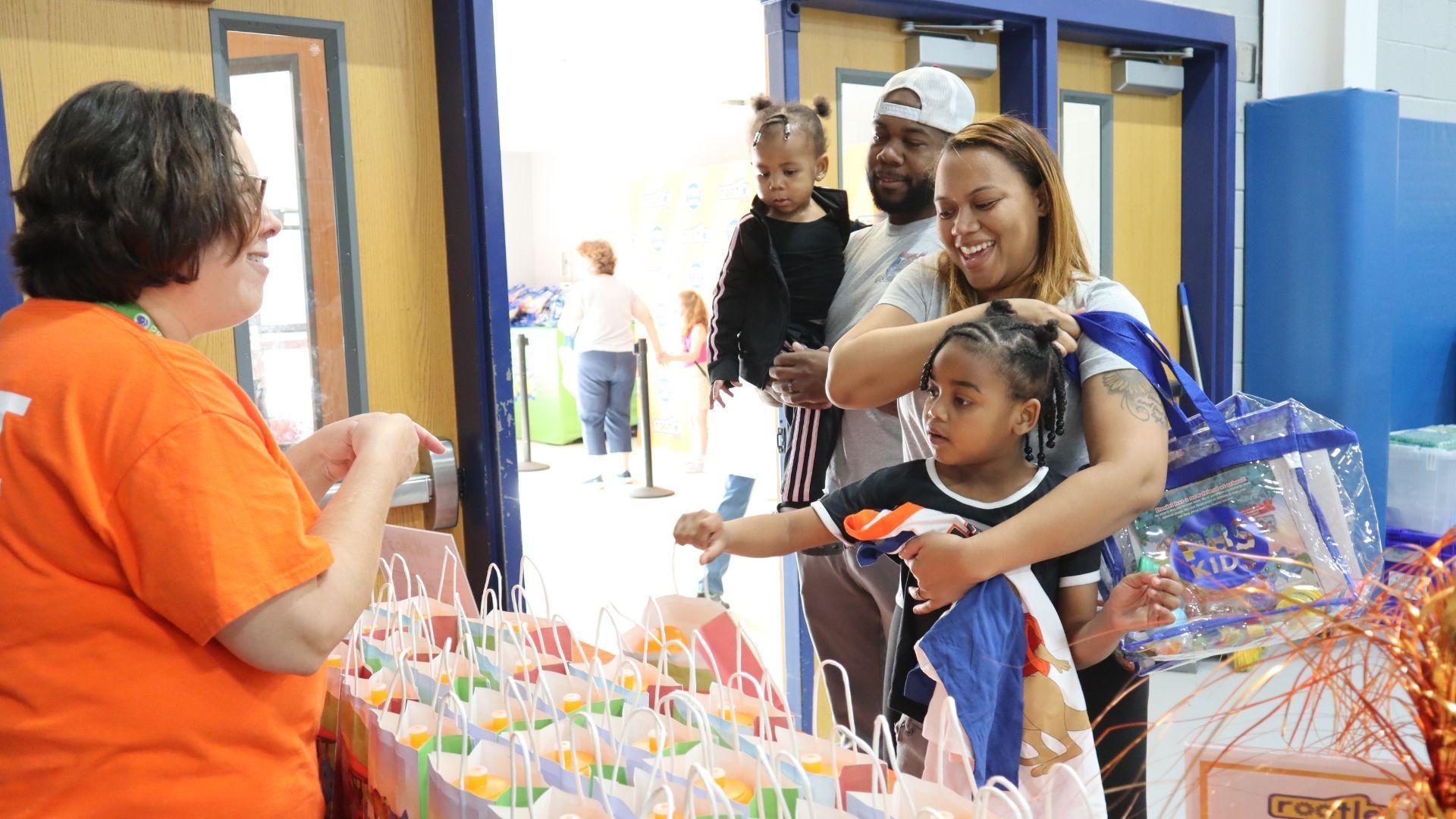 A Rootle volunteer hands out take home goodies to a family at a Rootle Roadster Tour stop.